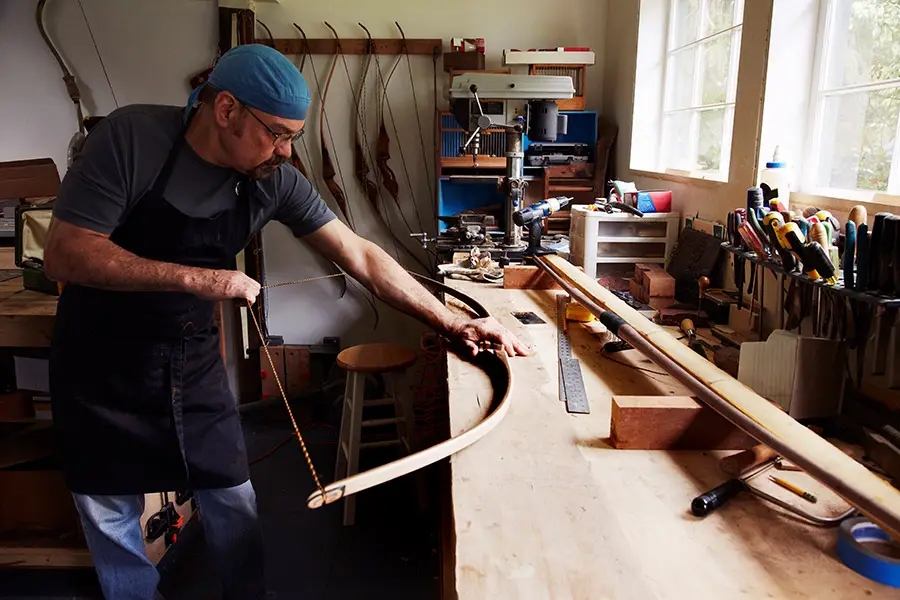 Ein Bogenbauer biegt Holz in seiner Werkstatt